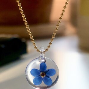 Petit pendentif rond en verre avec une fleur naturelle de Myosotis